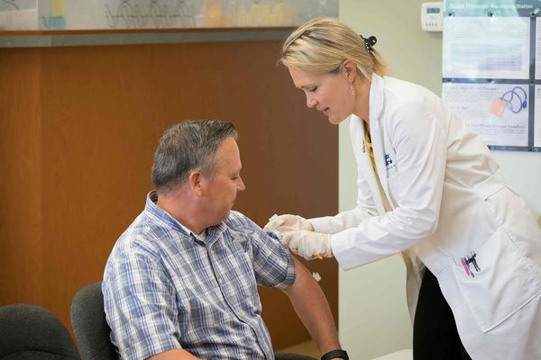 A pharmacist administers a shot to a patient Immunizations